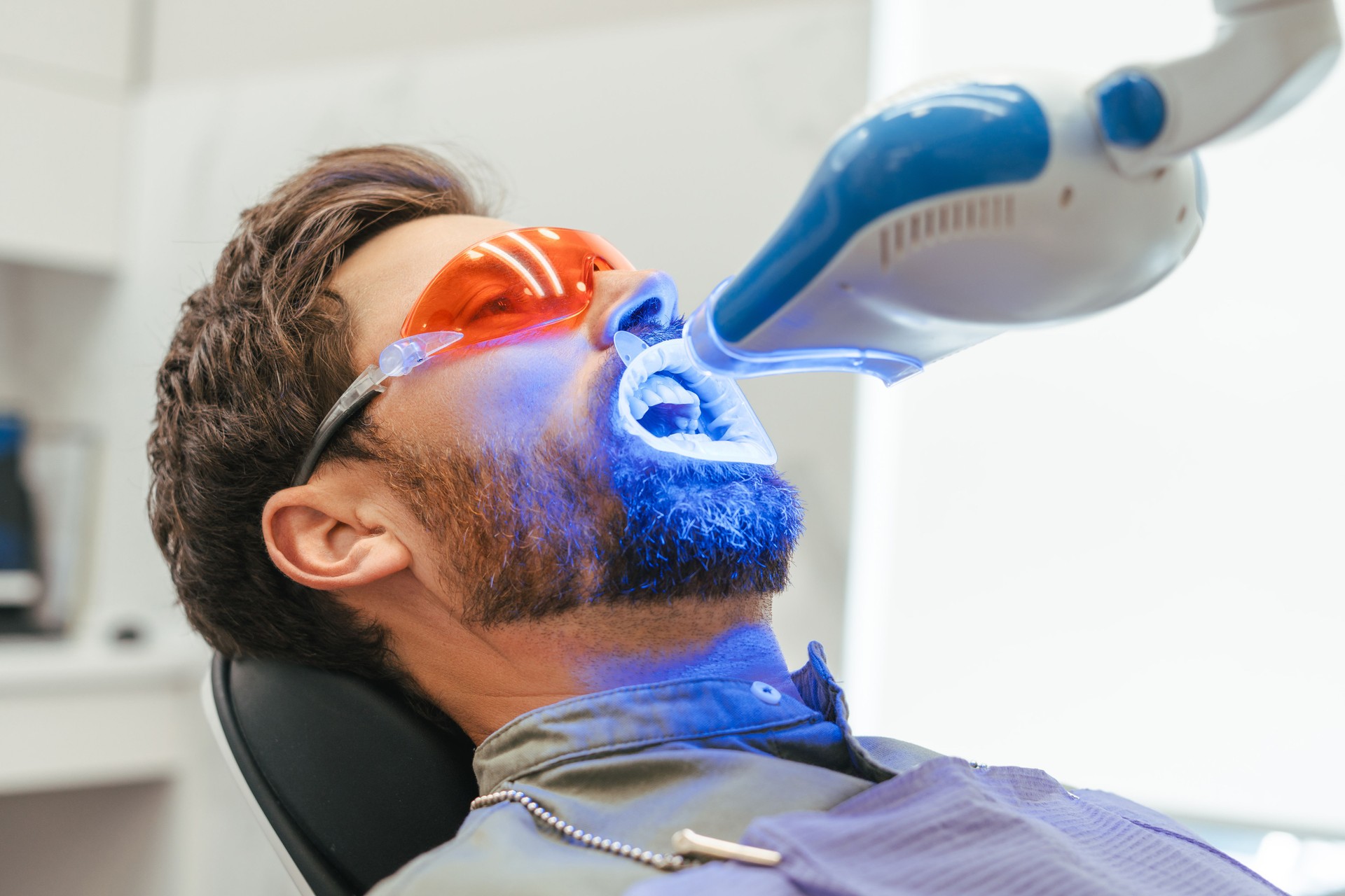 Patient undergoing teeth whitening procedure with uv light in dental clinic